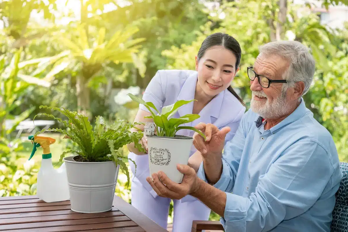 Nursing and old man holding a potted plant