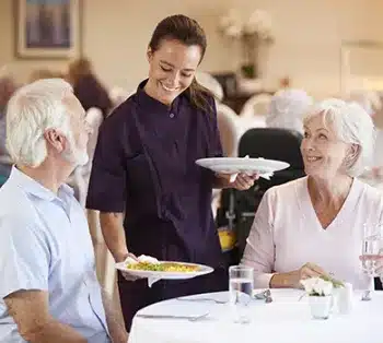 A waitress serving a couple of senior